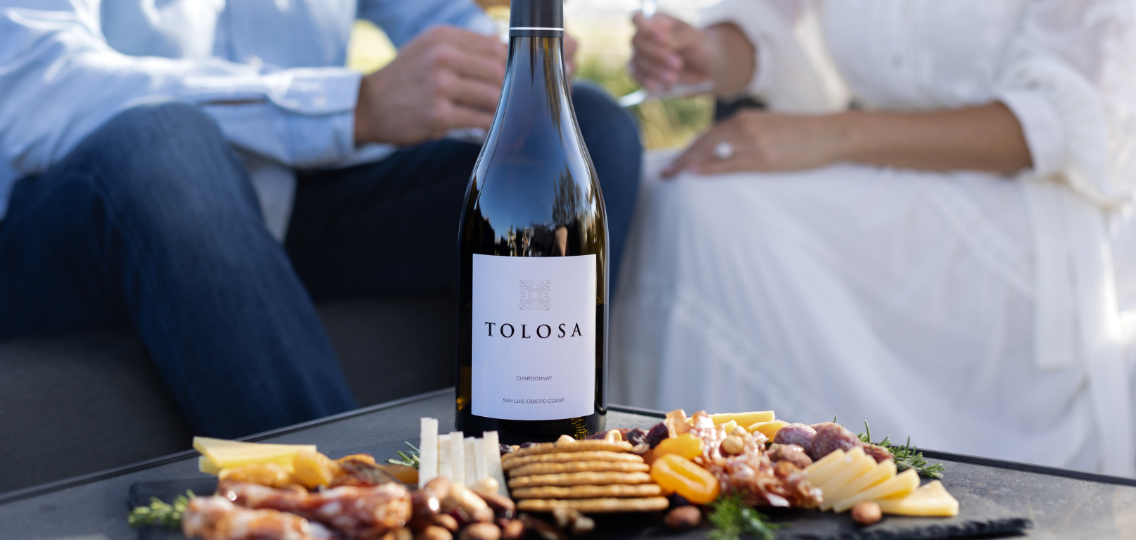 Image of two people drinking wine with a wine bottle at the table